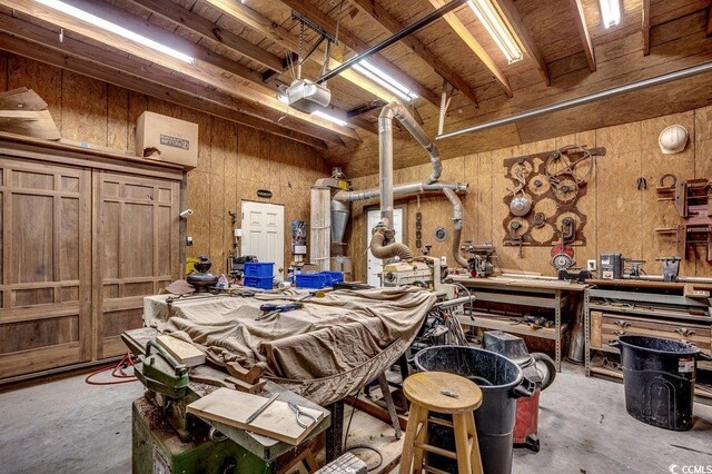 misc room with a garage, a workshop area, concrete flooring, and wooden walls