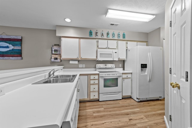 270 Pinehurst Ln Unit 9G, Pawleys Island, SC 29585 - kitchen with white appliances, a sink, light wood-style floors, light countertops, and white cabinetry