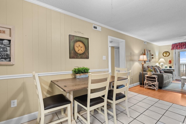 dining space with tile patterned flooring, ornamental molding, visible vents, and a textured ceiling