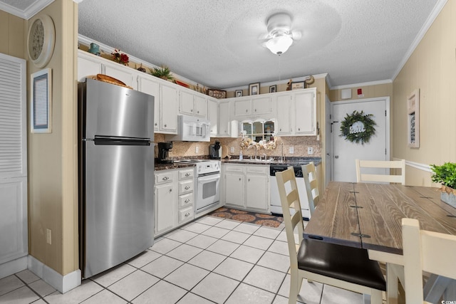 kitchen with white appliances, light tile patterned floors, white cabinets, crown molding, and dark countertops