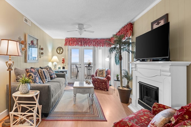 living area featuring visible vents, wood finished floors, a fireplace, and crown molding