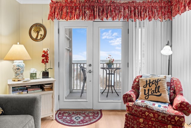 sitting room with a wealth of natural light, wood finished floors, french doors, and ornamental molding