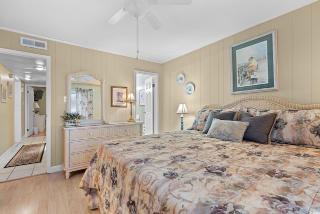 bedroom with visible vents, ornamental molding, ensuite bathroom, light wood-style floors, and a ceiling fan