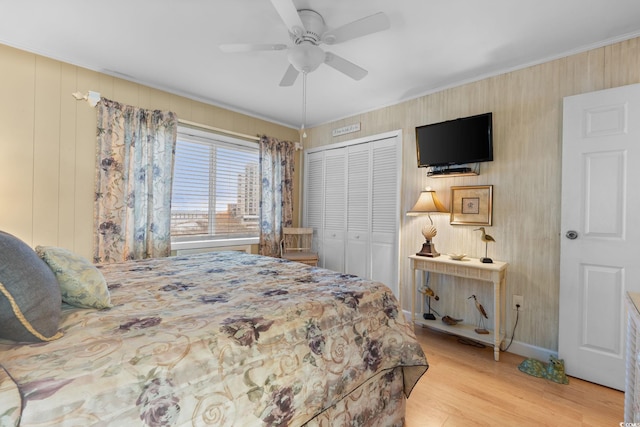 bedroom featuring a ceiling fan, baseboards, wood finished floors, ornamental molding, and a closet