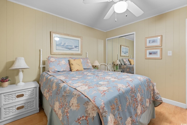 bedroom with crown molding, baseboards, wood finished floors, a closet, and a ceiling fan