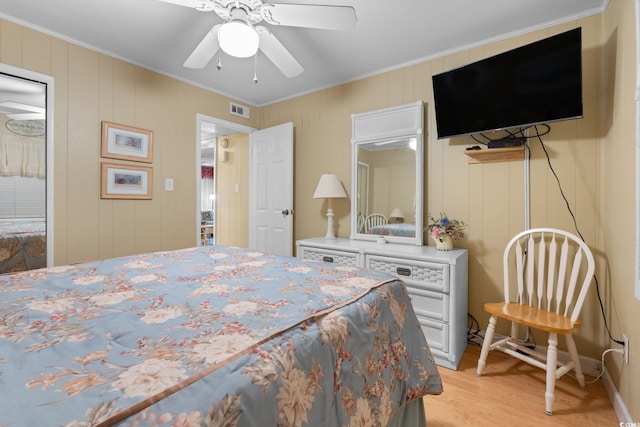 bedroom featuring ceiling fan, ornamental molding, visible vents, and light wood-type flooring