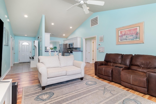 living area featuring light wood finished floors, visible vents, high vaulted ceiling, and ceiling fan