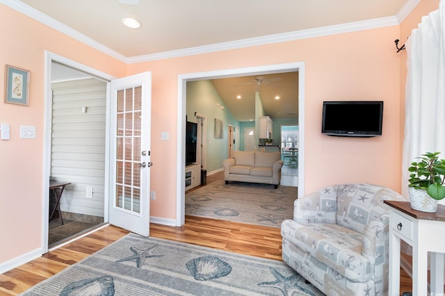 living area with ornamental molding, baseboards, and wood finished floors