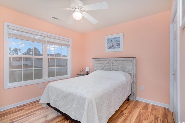 bedroom featuring a ceiling fan, wood finished floors, visible vents, and baseboards