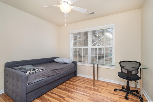 bedroom featuring a ceiling fan, wood finished floors, visible vents, and baseboards