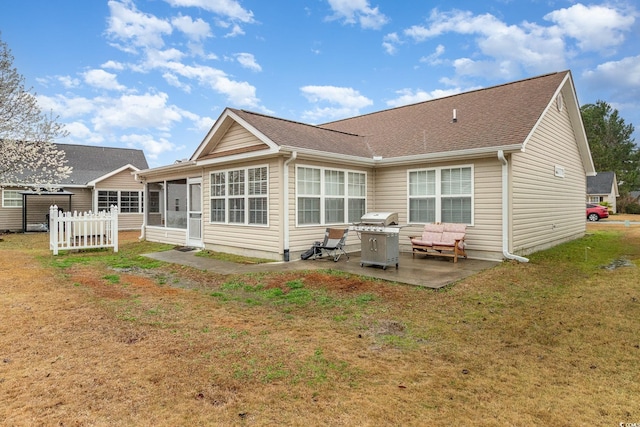 rear view of house with a yard, a patio area, a sunroom, and a shingled roof