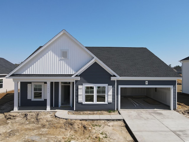 view of front of home featuring driveway, a porch, board and batten siding, an attached garage, and a shingled roof