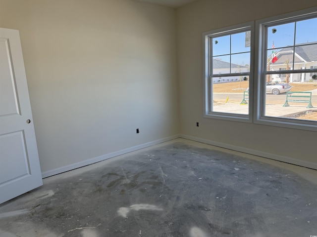 spare room with baseboards, a healthy amount of sunlight, and unfinished concrete floors