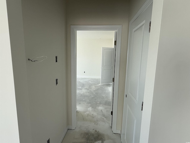 hallway featuring baseboards and unfinished concrete flooring