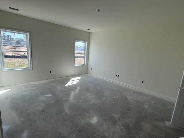 unfurnished room featuring unfinished concrete flooring, visible vents, and baseboards