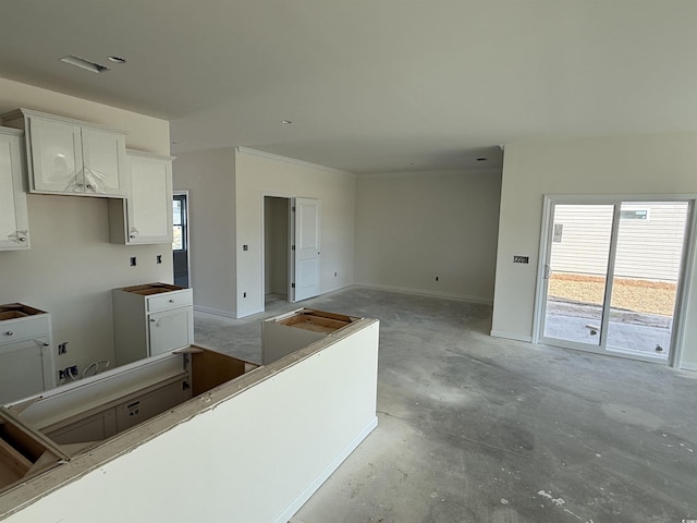 kitchen with baseboards, concrete floors, and white cabinetry