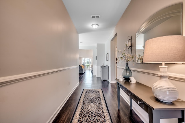 corridor with visible vents, baseboards, and wood finished floors