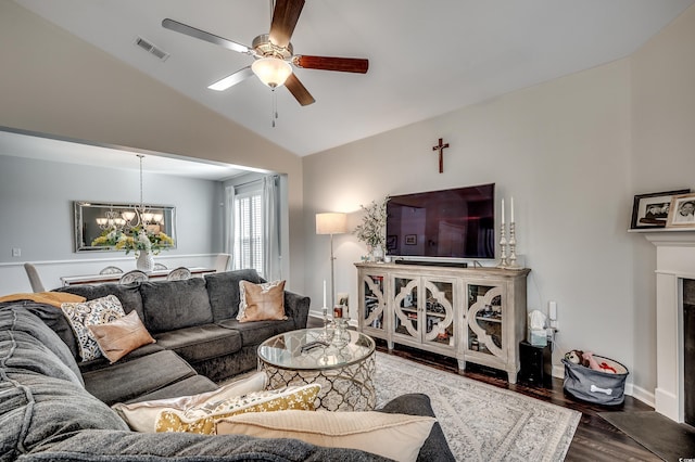 living room featuring visible vents, ceiling fan with notable chandelier, wood finished floors, baseboards, and vaulted ceiling