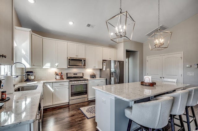 kitchen with visible vents, a sink, stainless steel appliances, backsplash, and a center island