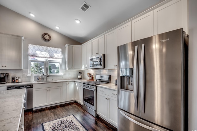 kitchen featuring visible vents, a sink, vaulted ceiling, appliances with stainless steel finishes, and tasteful backsplash