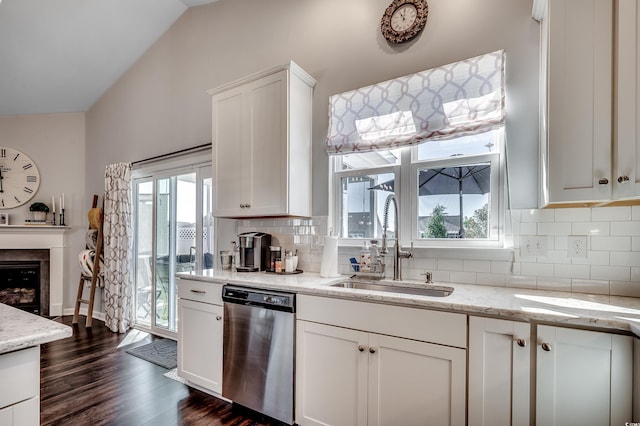 kitchen with lofted ceiling, a fireplace, a sink, white cabinets, and dishwasher