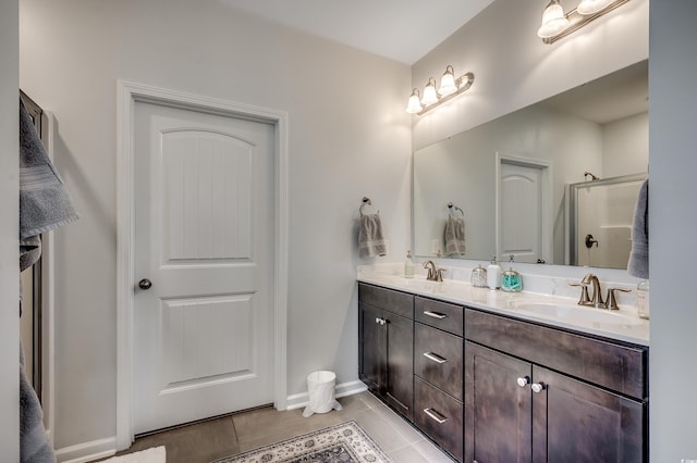 bathroom featuring tile patterned floors, double vanity, a shower with door, and a sink