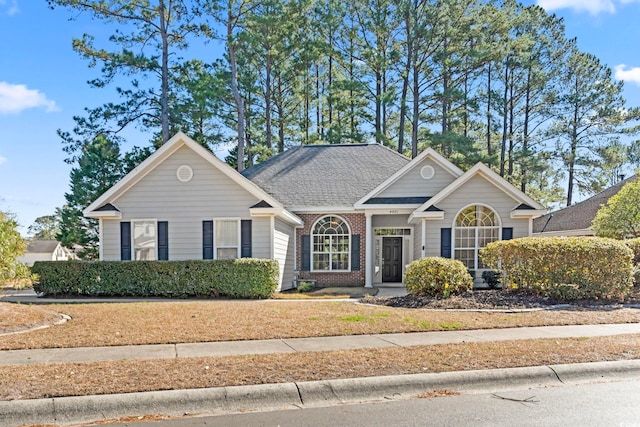 view of front of home with brick siding and roof with shingles