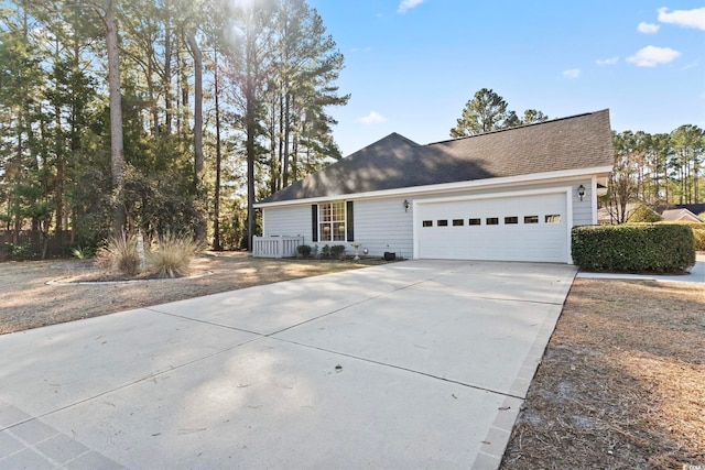 view of front facade featuring a garage, driveway, and roof with shingles