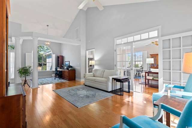 living room with visible vents, decorative columns, wood finished floors, high vaulted ceiling, and a ceiling fan