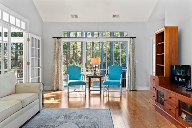 living area with visible vents, wood-type flooring, and baseboards