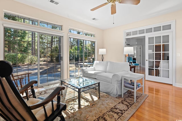 living room with visible vents, light wood-style flooring, and ceiling fan