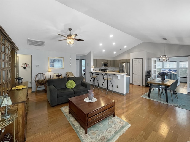 living room with vaulted ceiling, a ceiling fan, visible vents, and light wood finished floors