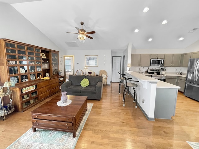 living area with vaulted ceiling, visible vents, and light wood-type flooring