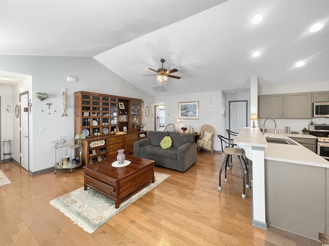 living area featuring a ceiling fan, baseboards, light wood-style flooring, recessed lighting, and vaulted ceiling