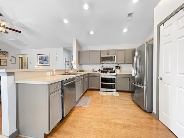 kitchen featuring visible vents, gray cabinetry, vaulted ceiling, stainless steel appliances, and a sink