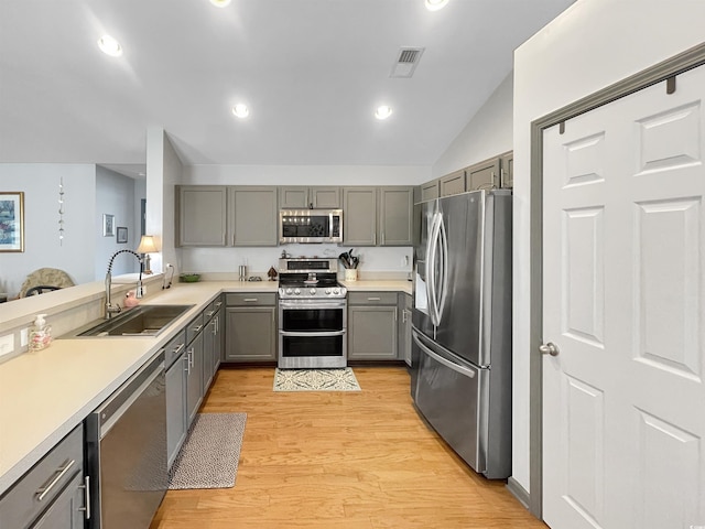 kitchen featuring light wood finished floors, visible vents, gray cabinetry, stainless steel appliances, and a sink