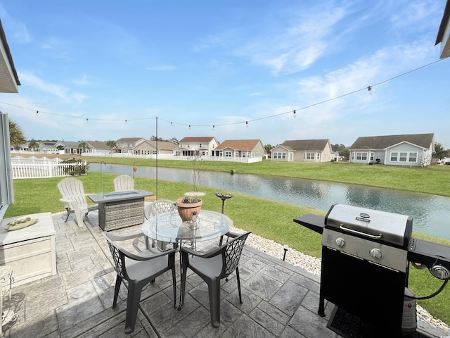 view of patio / terrace with a residential view, outdoor dining space, fence, and a water view