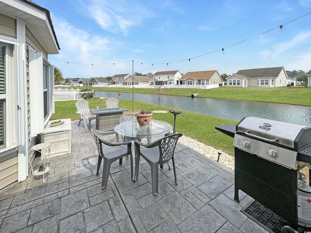 view of patio / terrace with fence, outdoor dining area, a water view, a residential view, and a grill