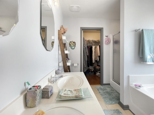 bathroom featuring a stall shower, a walk in closet, a garden tub, and a sink