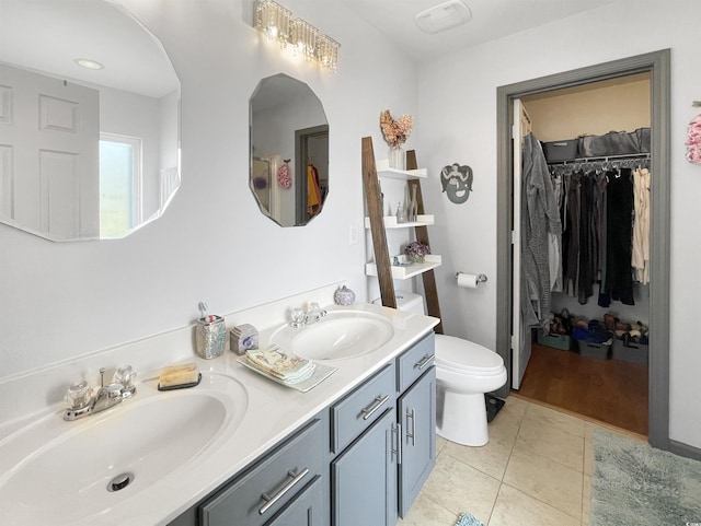 bathroom with tile patterned flooring, double vanity, toilet, and a sink