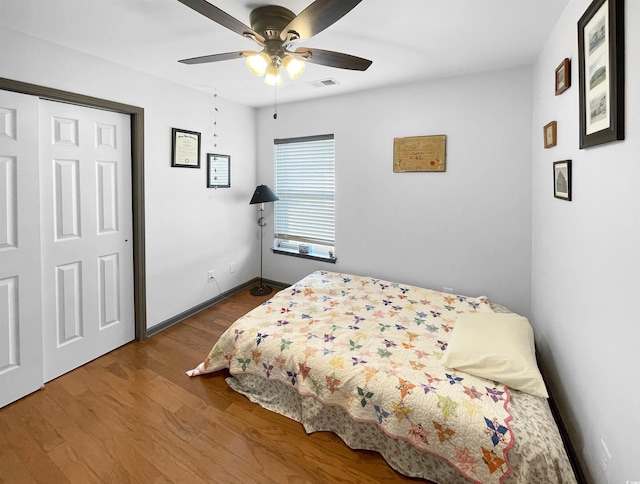 bedroom featuring a ceiling fan, wood finished floors, visible vents, and baseboards