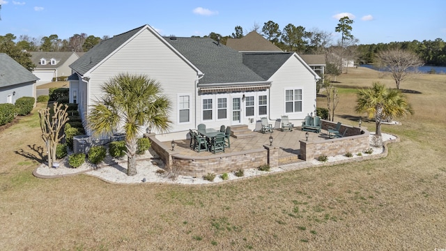 back of house with a lawn, entry steps, a shingled roof, and a patio