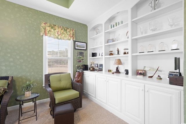 living area featuring built in shelves, wallpapered walls, and baseboards