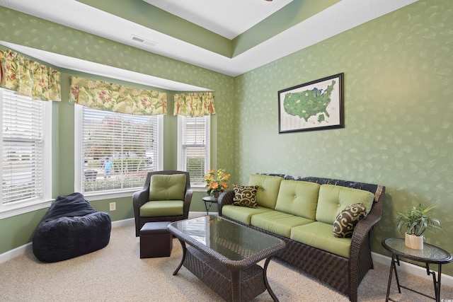 carpeted living room with visible vents, wallpapered walls, and baseboards