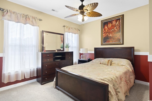 bedroom with a ceiling fan, visible vents, baseboards, and light carpet