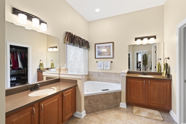 full bath featuring a sink, two vanities, a bath, and tile patterned flooring