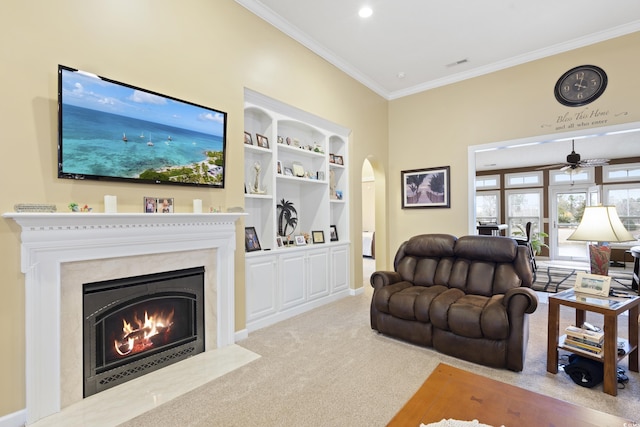 living area featuring built in features, arched walkways, a fireplace, carpet flooring, and crown molding