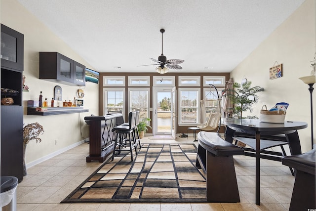 dining area with light tile patterned floors, a textured ceiling, a bar, and baseboards