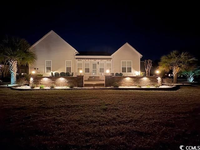 back of house at night featuring a patio area