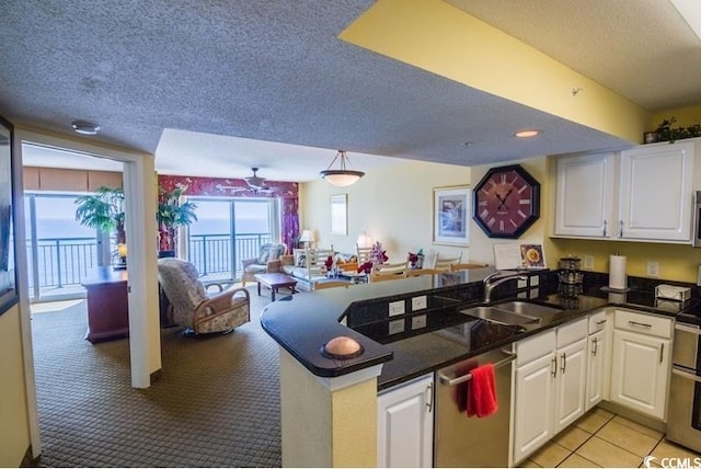 kitchen featuring a peninsula, a sink, stainless steel appliances, white cabinets, and a textured ceiling